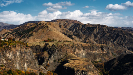 Obraz premium Mountain valley landscape with autumn forest and dramatic hills under blue sky