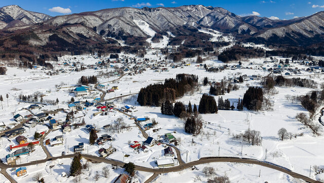 Sunny winter day overlooking a snowy rural valley and mountains with blue sky