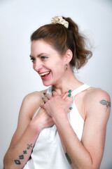 Naklejka premium Natürliches Frauenportrait mit sanftem Lächeln und grün lackierten Nägeln. Warmes Licht, Tattoo-Detail und zarte Pose – modernes Beauty- und Lifestyle-Foto mit authentischer Ausstrahlung.