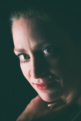 Naklejka premium Low-Key-Portrait eines Models im Mantel vor dunklem Hintergrund. Dramatisches Licht, starke Schatten und roter Lippenstift setzen elegante, ausdrucksstarke Akzente.