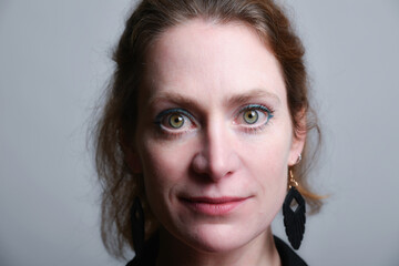 Fototapeta premium Low-Key-Portrait eines Models im Mantel vor dunklem Hintergrund. Dramatisches Licht, starke Schatten und roter Lippenstift setzen elegante, ausdrucksstarke Akzente.