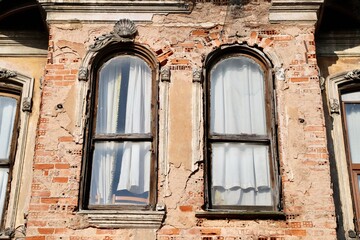 Detail of Weathered Historic Brick Building Facade with Peeling Plaster and Arched Windows