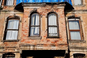Detail of Weathered Historic Brick Building Facade with Peeling Plaster and Arched Windows