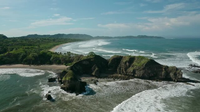 Aerial drone view of rocky headland at Guiones Beach in Nosara, Costa Rica, with waves crashing along the shoreline