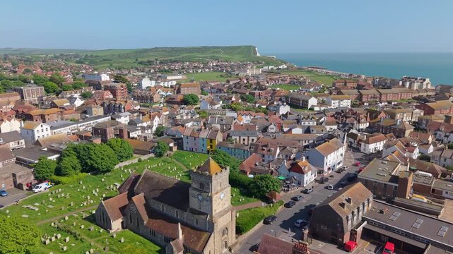 Drone shot starting at St. Leonard's Church, ascending to reveal the sunny town of Seaford, with the sparkling English Channel and beach stretching into the background.