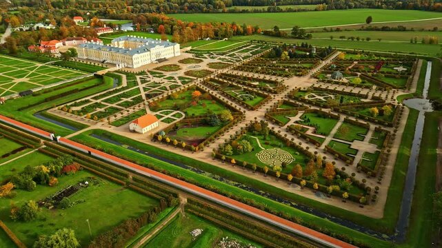Aerial view of grand Baroque palace with symmetrical formal gardens and geometric parterres in Europe.