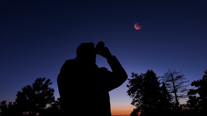 Fototapeta premium Amateur astronomer using binoculars for observing stars, planets, Moon and other celestial objects.