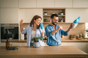 Couple dancing and singing while house cleaning in kitchen