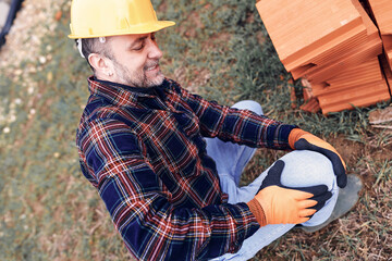 Construction worker having a accident and injured knee and leg on a construction site outdoors.