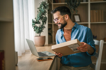 Obraz premium Young man receiving online shopping delivery at home office