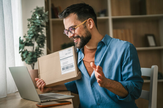 Happy man unboxing online shopping package at home