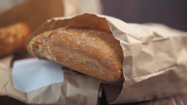 Close up of artisan bread in paper bag on rustic wooden table with rotating motion