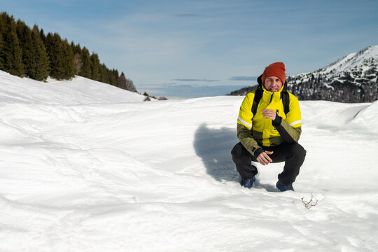 Tourist portrayed on a snow-capped mountain. The man is forty-two years old, of Caucasian origin and wears a yellow and green ski jacket