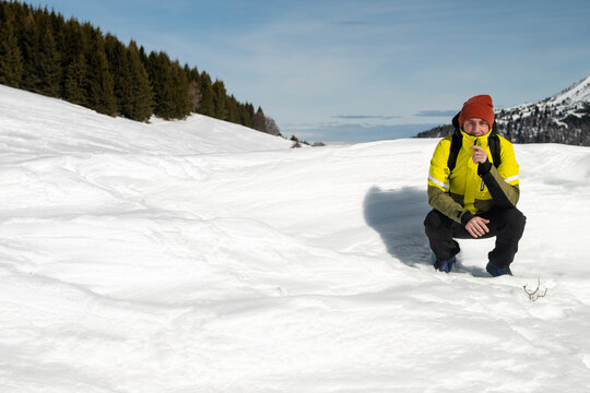 Tourist portrayed on a snow-capped mountain. The man is forty-two years old, of Caucasian origin and wears a yellow and green ski jacket