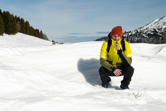 Tourist portrayed on a snow-capped mountain. The man is forty-two years old, of Caucasian origin and wears a yellow and green ski jacket