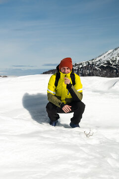 Tourist portrayed on a snow-capped mountain. The man is forty-two years old, of Caucasian origin and wears a yellow and green ski jacket