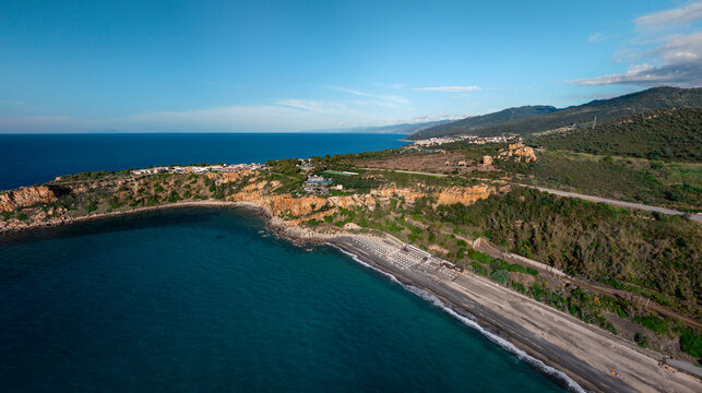 Aerial view of Spiaggia Torre Conca where cerulean waters meet rugged cliffs and a dark sandy beach, Finale, Sicilia, Italy.