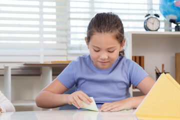 Naklejka premium Caucasian preteen girl folding green paper during classroom craft activity learning origami creativity imagination and focus developing childhood skill through handmade education project workshop