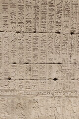 Ancient stone wall carved with detailed Egyptian hieroglyphs and symbols