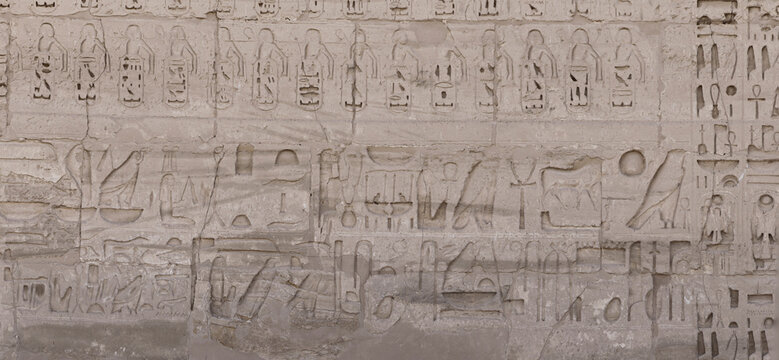 Ancient carved hieroglyphs depicting symbols on stone wall
