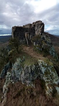 Vertical aerial drone shot of ancient castle ruins on rocky hill