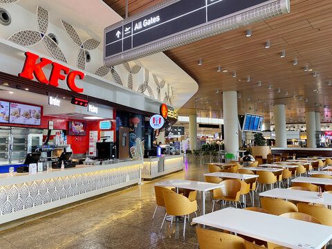 Mumbai, India - October 22, 2025: KFC fast food outlet inside Chhatrapati Shivaji International Airport with dining area and signage for all gates visible in the background