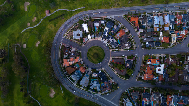Aerial view of a circular street formation with houses around a central green space, adjacent to a golf course, Coronado, California, United States.