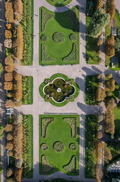 Aerial view of manicured rose gardens with symmetrical patterns and a central fountain create a captivating tapestry of green and gold tones, Volksgartenbrunnen, Vienna, Austria.