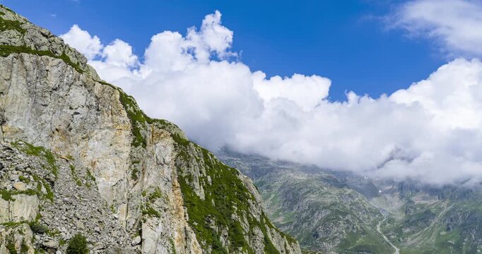 Clouds flowing over the green alpine peaks of Susten Pass in the Swiss Alps, Switzerland. Hyperlapse, Aerial drone fpv, copy space
