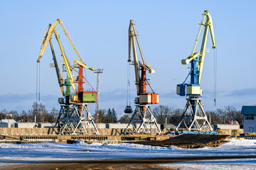 Cranes lifting containers at a busy shipping yard during daylight hours in winter