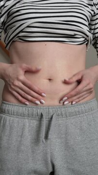 Vertical close up of woman pinching belly fat. Concept of weight loss, fitness motivation, gut health and healthy lifestyle transformation in 4K.