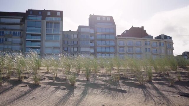 Walking past sand dune with grass and beach front houses in Knokke Belgium