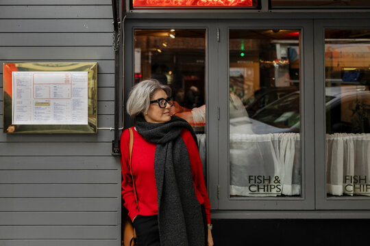 Woman thinking while waiting outside a fish and chips restaurant in London