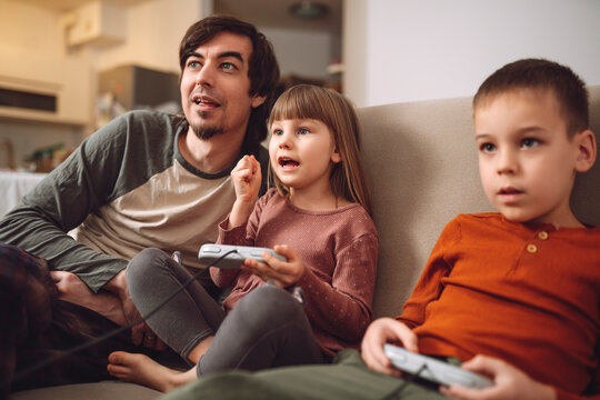 Father playing videogames with son and daughter at home