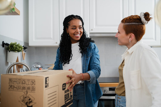 Friends packing boxes together in kitchen during home move