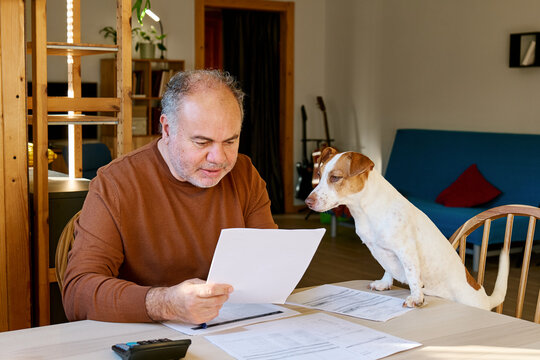 Man reviewing household budget and finances with dog at home
