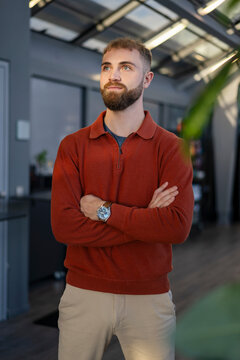 Young man in a red sweater posing confidently in an office environment