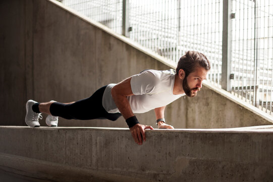 Man doing push up outdoors on concrete urban structure