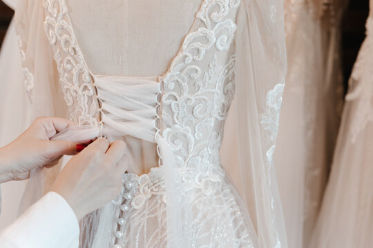 Seamstress sewing corset back of wedding dress in fashion atelier