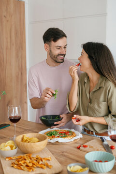 Happy couple making and enjoying homemade pizza together at home