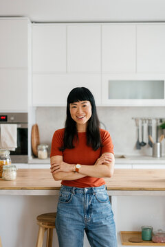 Confident woman standing and smiling in a modern kitchen