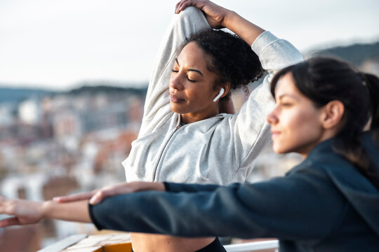 Women stretching outdoors in sportswear with cityscape in background