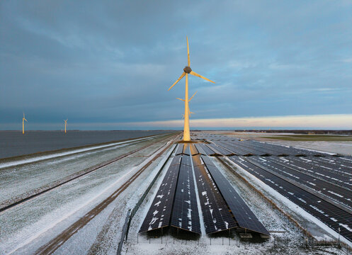 Wind turbines and solar panel farm on snowy dyke Flevoland the Netherlands