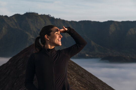 Smiling explorer hiking at sunrise near volcano crater in Java Indonesia