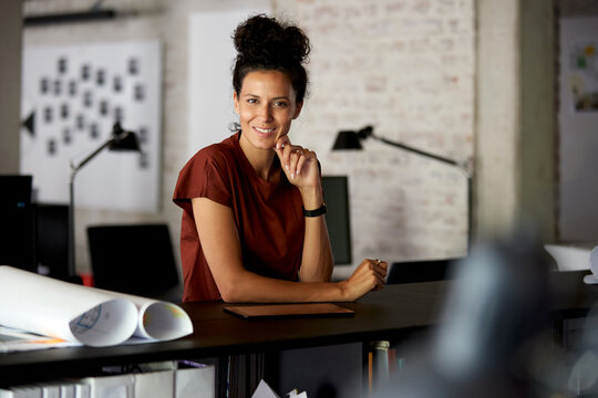 Smiling architect businesswoman working at desk in modern office