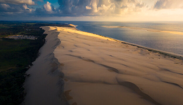 Aerial view of the golden sand meeting the sea in a dance of light and shadow under a dramatic sky, Marseille, Provence-Alpes-Cote d'Azur, France.