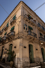 Sicilian baroque corner building with balconies and green shutters