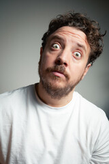 Fototapeta premium Man with Curly Hair and Beard Looking Upward with a Wide-Eyed Expression