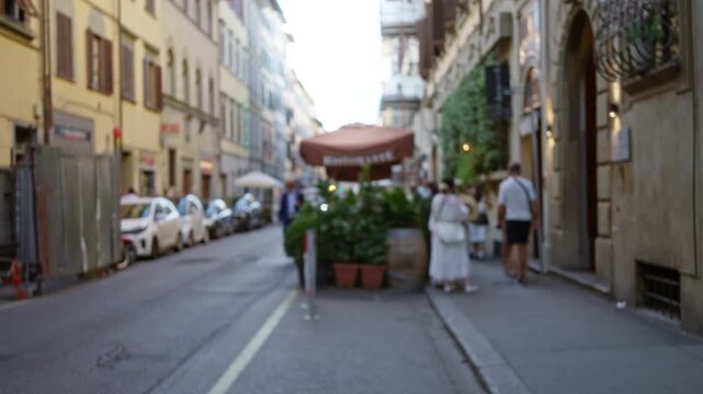 Florence street scene with blurred bokeh and defocused shallow focus on row of buildings and roadside cafe plants, soft background street; background backplate copyspace backdrop.