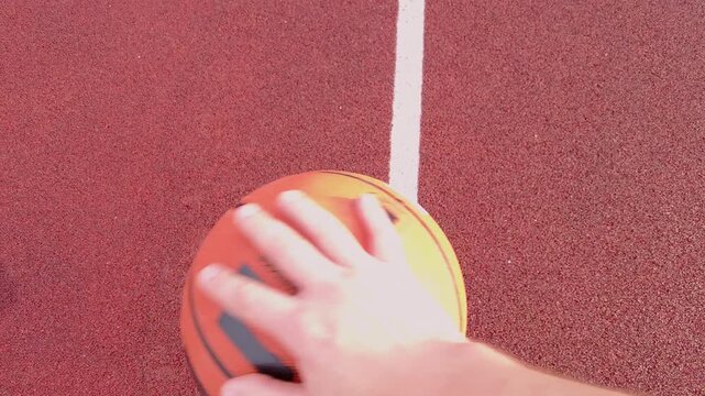 Male Hand Dribbling Basketball on Outdoor Court
